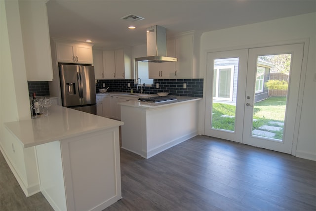 kitchen with white cabinetry, french doors, wall chimney range hood, kitchen peninsula, and stainless steel fridge