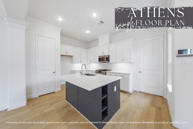 kitchen featuring white cabinetry, sink, stainless steel appliances, light hardwood / wood-style flooring, and a kitchen island with sink