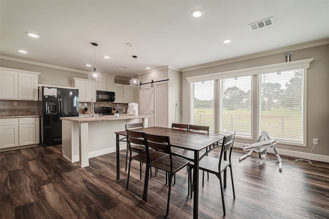 dining room with dark wood-type flooring, ornamental molding, sink, and a barn door