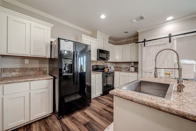 kitchen with sink, black appliances, a barn door, crown molding, and white cabinets