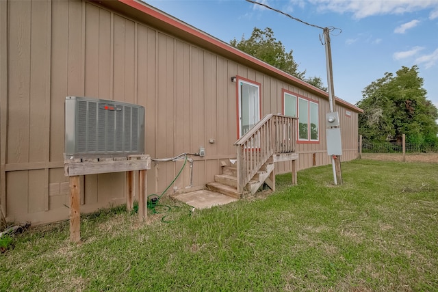 view of side of home with a yard and central AC