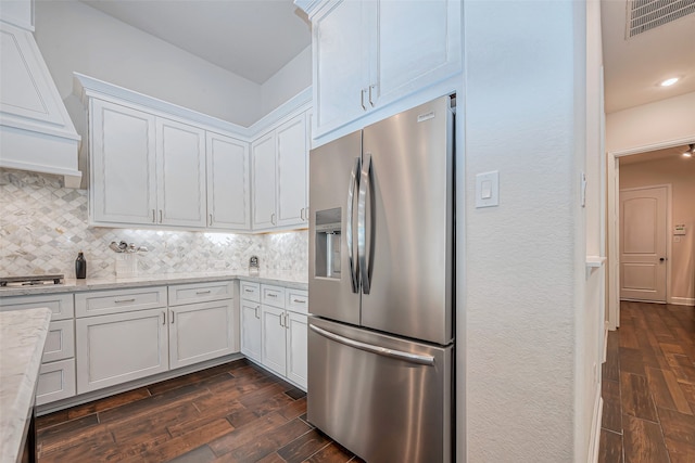 kitchen with dark wood-type flooring, stainless steel fridge with ice dispenser, light stone counters, and white cabinets