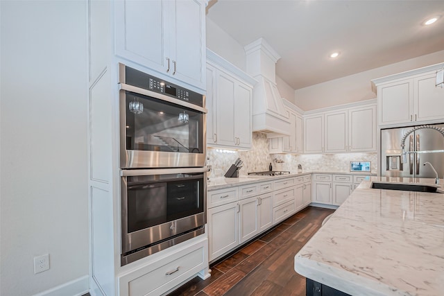 kitchen with stainless steel double oven, white cabinetry, dark hardwood / wood-style flooring, sink, and decorative backsplash