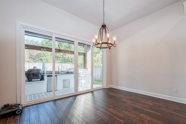 unfurnished room with dark hardwood / wood-style flooring, a notable chandelier, and a healthy amount of sunlight