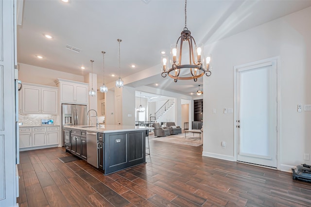 kitchen with white cabinetry, hanging light fixtures, dark wood-type flooring, and an island with sink