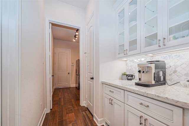 bar with dark wood-type flooring, light stone countertops, decorative backsplash, and white cabinets