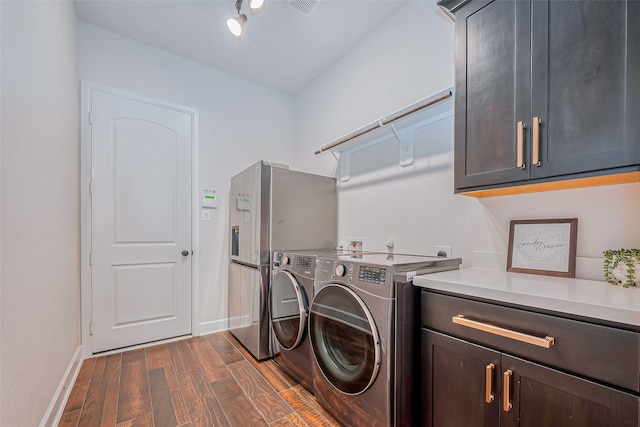 clothes washing area featuring dark wood-type flooring, cabinets, and washing machine and clothes dryer