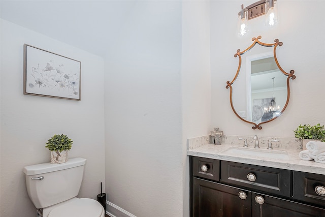 bathroom featuring vanity, toilet, and an inviting chandelier