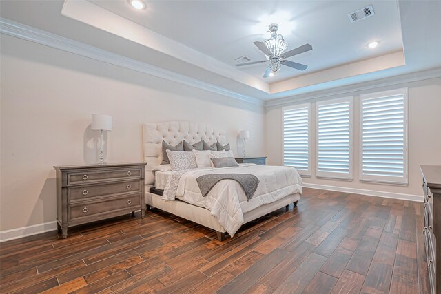 bedroom featuring dark hardwood / wood-style flooring, crown molding, ceiling fan, and a raised ceiling