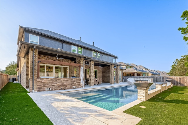 rear view of property featuring a fenced in pool, a patio, a lawn, and ceiling fan