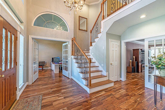 entryway featuring ornamental molding, french doors, dark hardwood / wood-style floors, and a towering ceiling