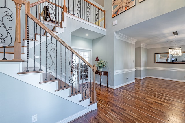 stairs featuring wood-type flooring, an inviting chandelier, and crown molding