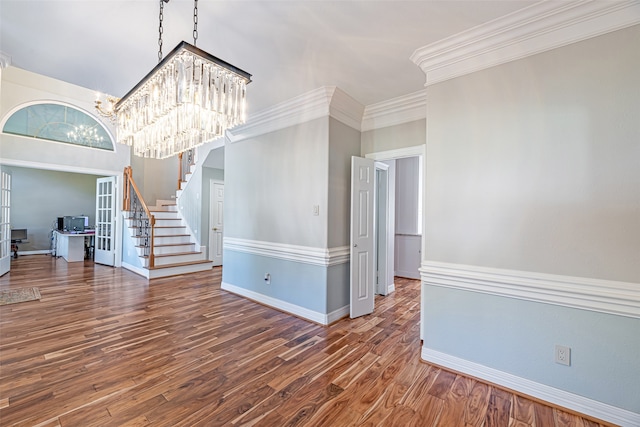 unfurnished living room featuring dark hardwood / wood-style flooring, a high ceiling, a notable chandelier, and ornamental molding