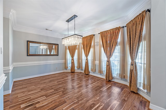 spare room featuring dark wood-type flooring, an inviting chandelier, and crown molding