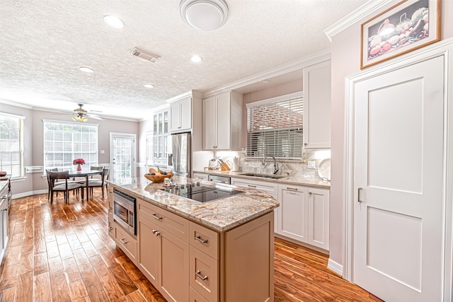 kitchen with appliances with stainless steel finishes, light hardwood / wood-style floors, white cabinetry, and a center island