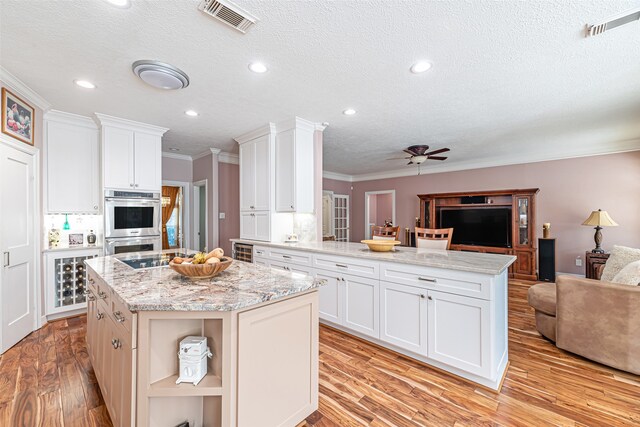 kitchen featuring light hardwood / wood-style floors, white cabinetry, kitchen peninsula, and a center island