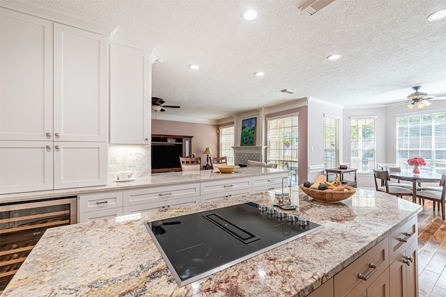 kitchen featuring black electric stovetop, beverage cooler, white cabinets, backsplash, and light wood-type flooring