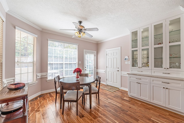 dining room featuring a textured ceiling, dark hardwood / wood-style floors, crown molding, and ceiling fan