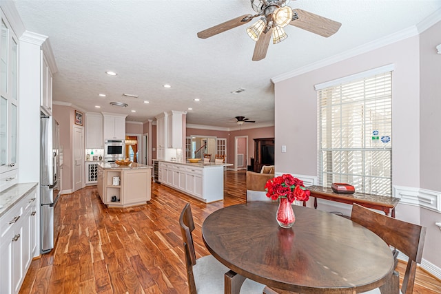 dining room featuring ornamental molding, light hardwood / wood-style floors, and a textured ceiling