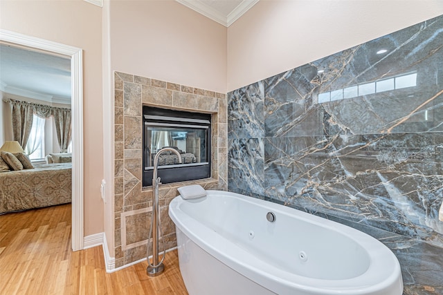 bathroom with tile walls, hardwood / wood-style floors, a tile fireplace, ornamental molding, and a bath