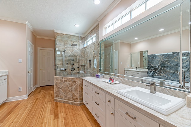 bathroom featuring a textured ceiling, wood-type flooring, vanity, tiled shower, and crown molding