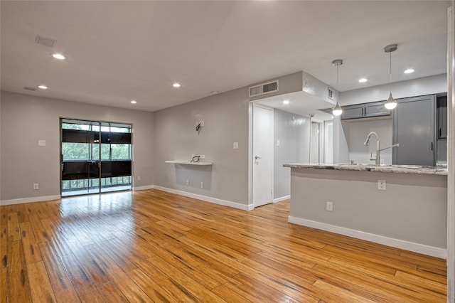 unfurnished living room with sink and light wood-type flooring