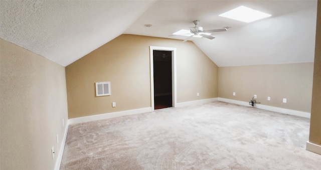 additional living space with lofted ceiling with skylight, carpet, a textured ceiling, and ceiling fan