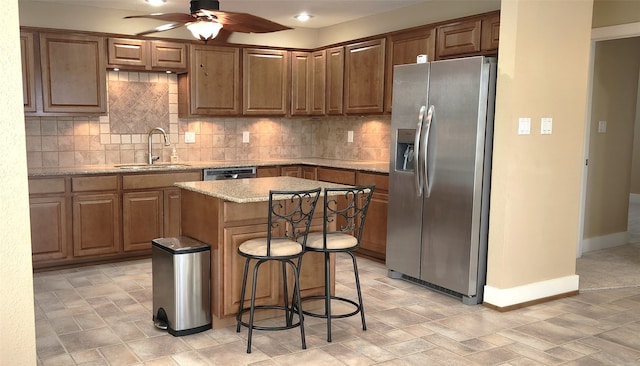 kitchen featuring decorative backsplash, a kitchen island, a kitchen bar, sink, and stainless steel appliances