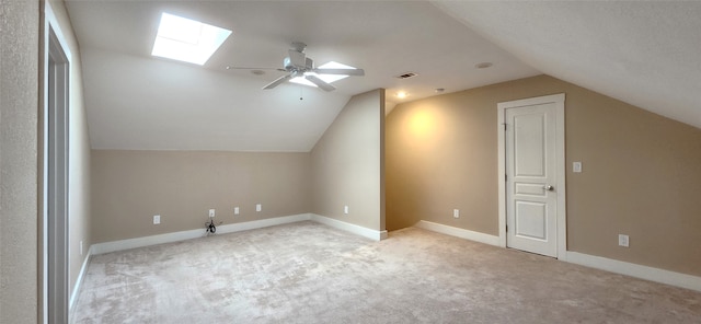 additional living space with ceiling fan, vaulted ceiling with skylight, and light colored carpet