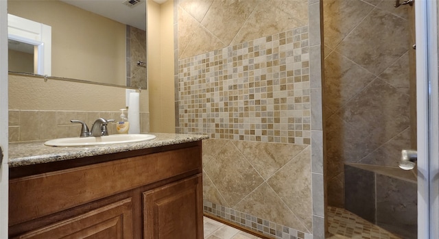 bathroom featuring tile walls, vanity, and tiled shower