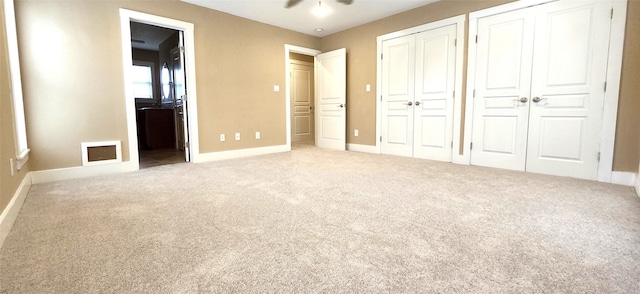 unfurnished bedroom with multiple closets, carpet, and ceiling fan