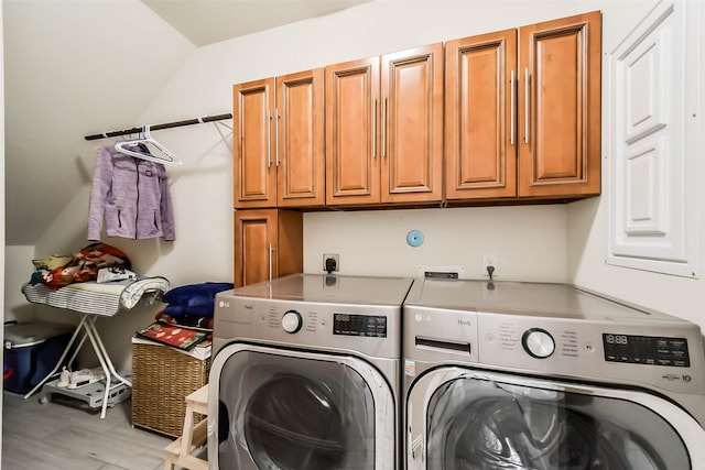 washroom featuring light hardwood / wood-style flooring, washing machine and dryer, and cabinets