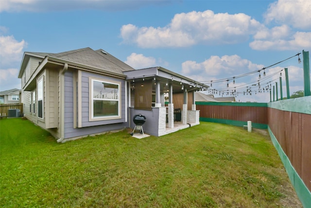 back of property featuring central AC unit and a yard