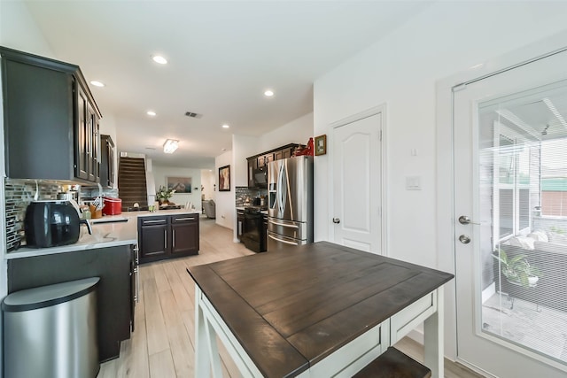 kitchen featuring dark brown cabinets, stainless steel fridge, light wood-type flooring, and decorative backsplash