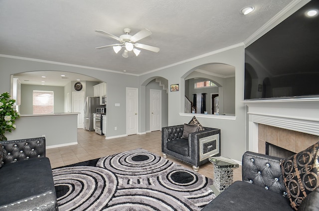 living room featuring a tile fireplace, light tile patterned flooring, and crown molding