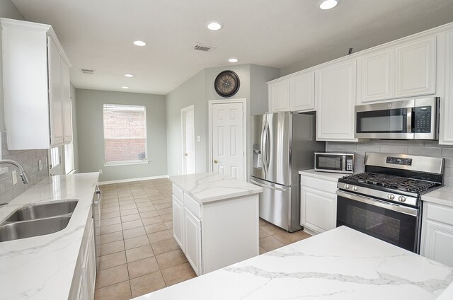 kitchen featuring a center island, sink, light stone counters, and stainless steel appliances