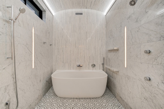 bathroom featuring tile walls, tile patterned floors, separate shower and tub, and vaulted ceiling