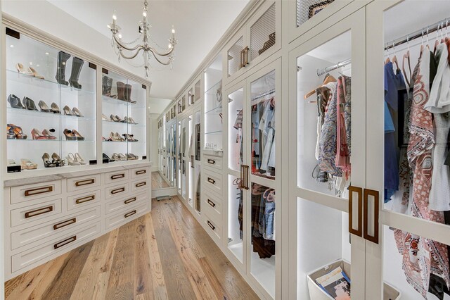 walk in closet with light hardwood / wood-style flooring and a notable chandelier