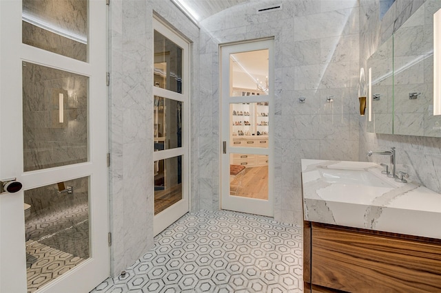 bathroom with tile walls, vanity, and walk in shower