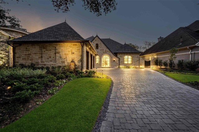 french country inspired facade with a yard