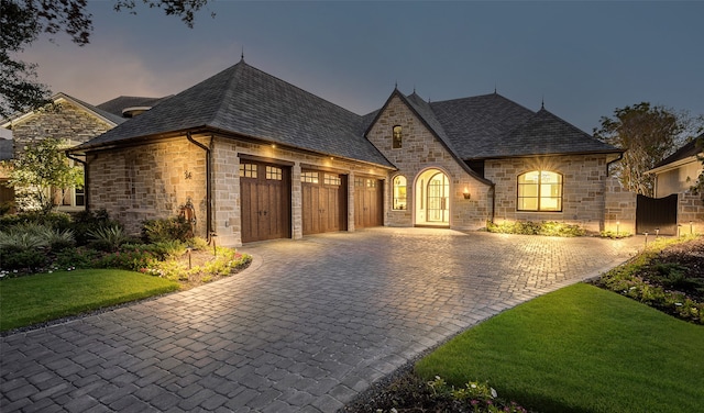 french country home with a yard and a garage