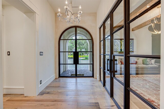 entrance foyer with french doors, light hardwood / wood-style flooring, and a chandelier