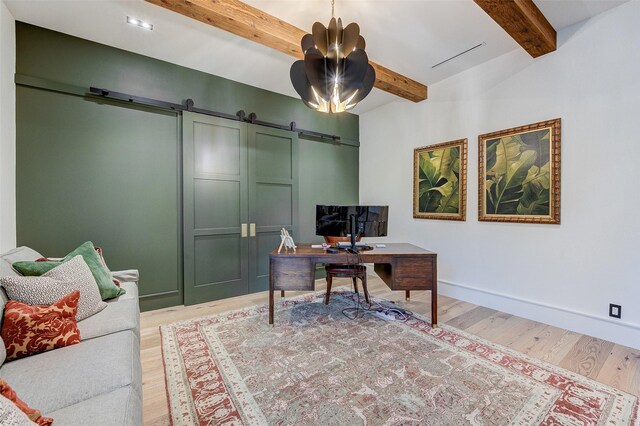 office area featuring beamed ceiling, light hardwood / wood-style flooring, and a barn door