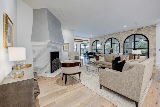 living room with light hardwood / wood-style floors, a wealth of natural light, and a high end fireplace