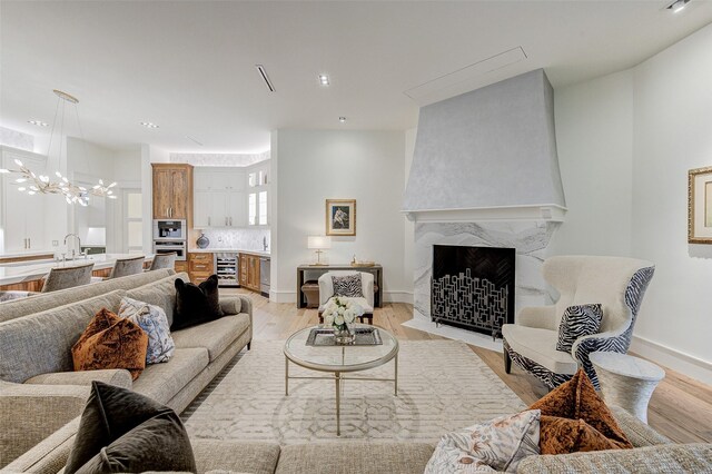 living room featuring a notable chandelier, a premium fireplace, light hardwood / wood-style flooring, and beverage cooler