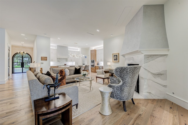 living room with a notable chandelier, light hardwood / wood-style flooring, and a fireplace