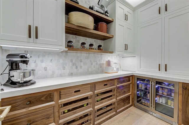 interior space featuring white cabinets, tasteful backsplash, light stone countertops, light wood-type flooring, and beverage cooler