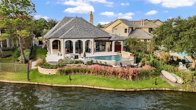 rear view of property featuring a patio area, a yard, and a water view