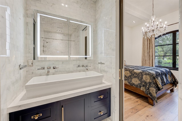 bathroom with tile walls, hardwood / wood-style floors, a tile shower, and an inviting chandelier