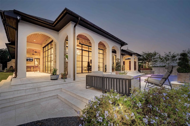 back house at dusk featuring a patio area and an outdoor living space